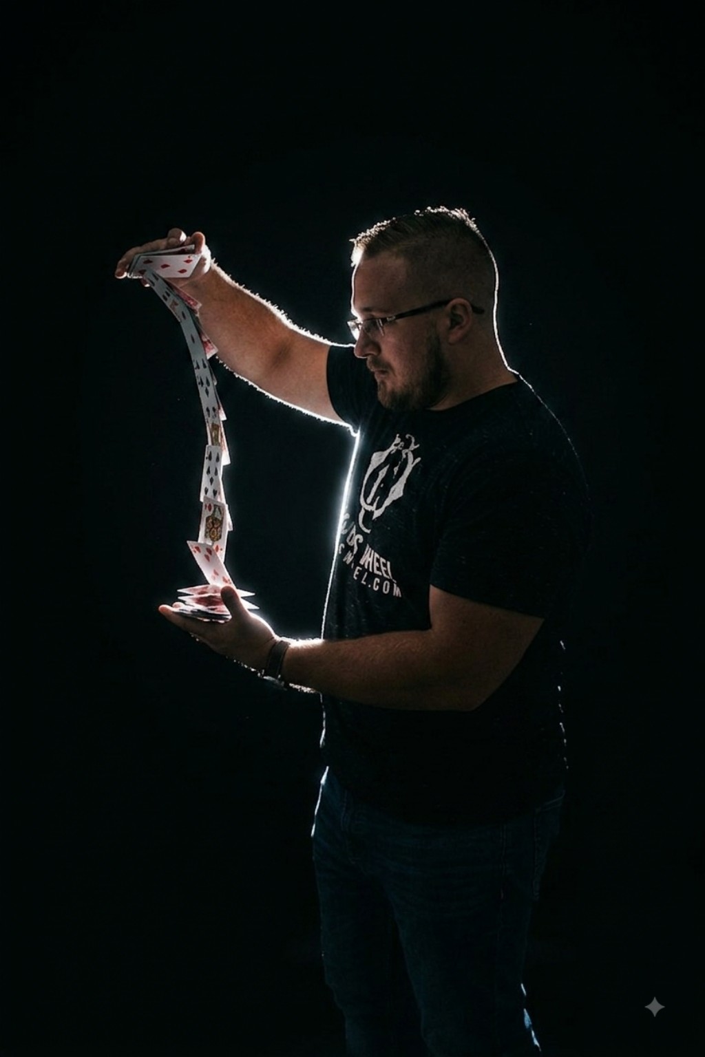 Chris Wheel performing a cascade of playing cards in a dark studio