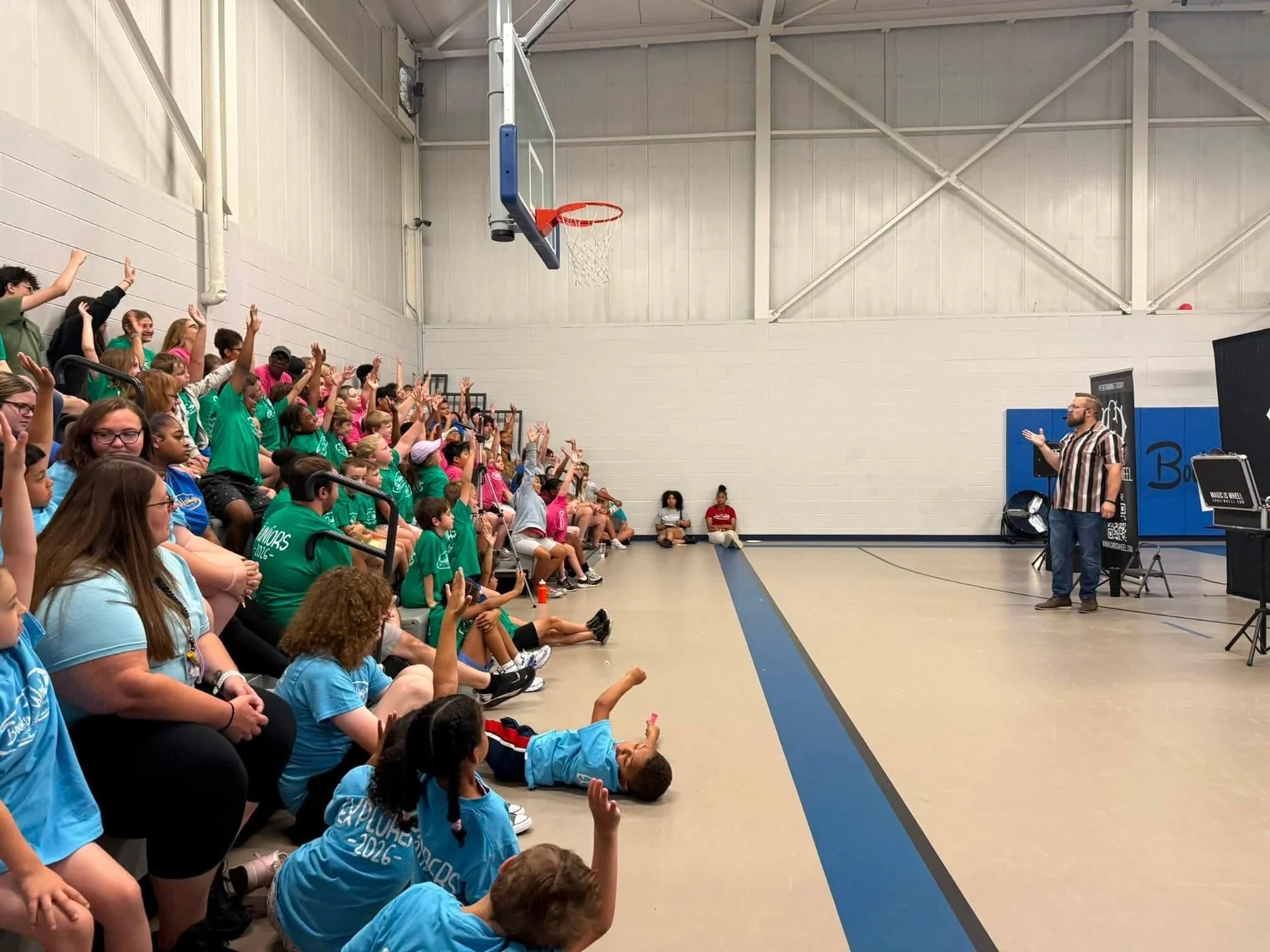 Students raising their hands to join Chris Wheel’s school magic show