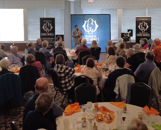 Chris Wheel performing a comedy magic show for a seated audience